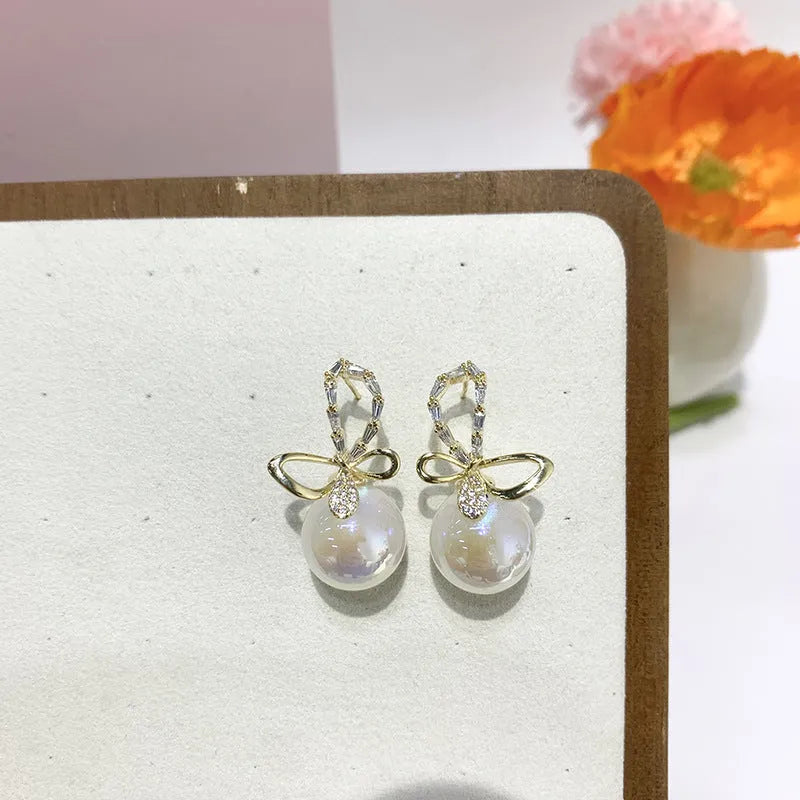 Pair of minimally designed gold tone drop earrings with single faux pearl