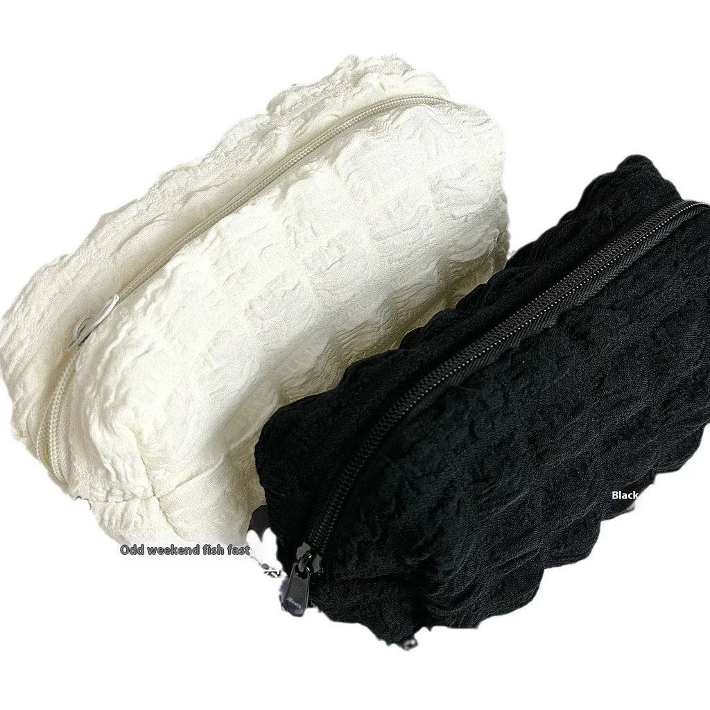 Beige and black fabric cream puff style pencil case made from polyester.