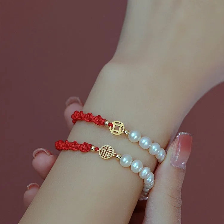 Women's pearl bracelet with gold-plated fu charm on braided red rope