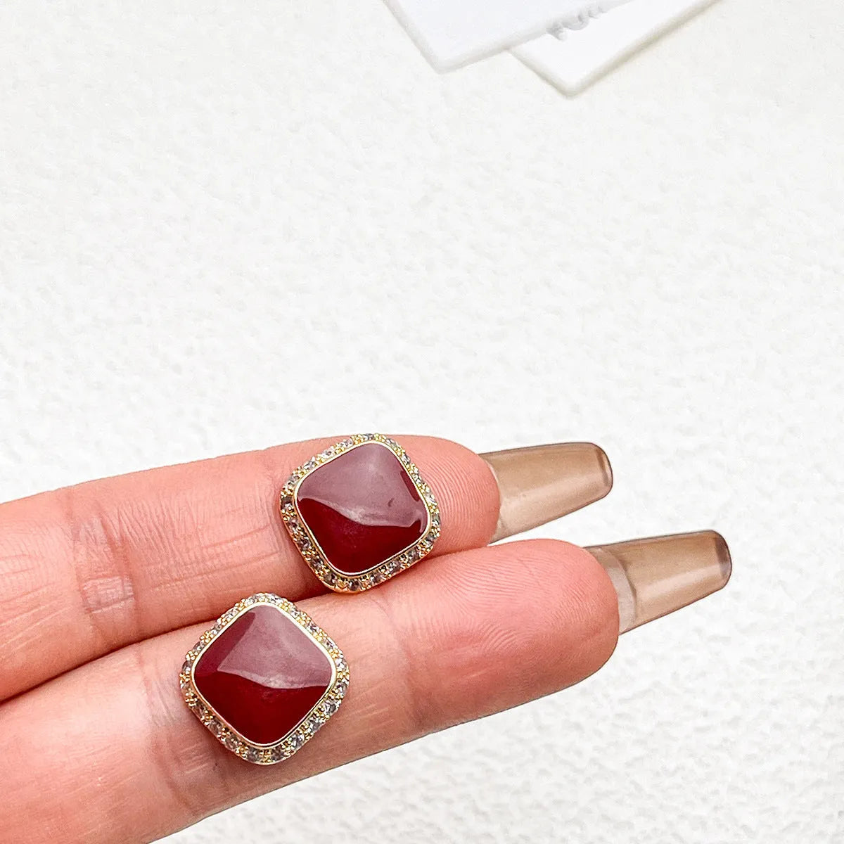 A pair of red geometric square alloy earrings with an inlaid plate design, showing front view.
