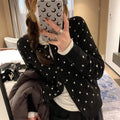 Women's grey knitted cardigan with white crochet flower embroidery on the front.