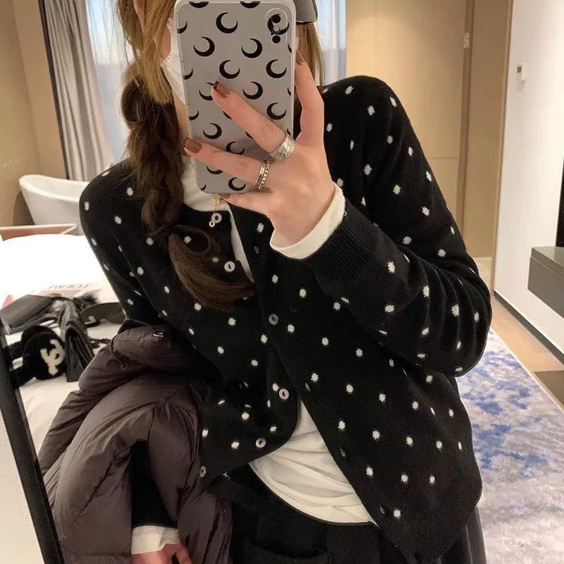 Women's grey knitted cardigan with white crochet flower embroidery on the front.