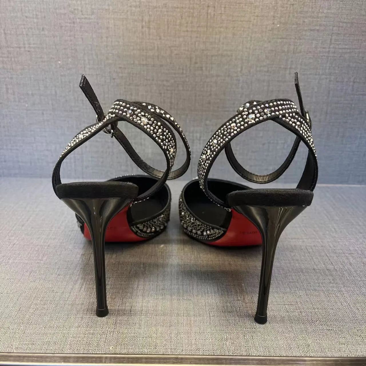 Women's black high-heeled shoes with a red sole, showing stiletto heel and pointed toe design.
