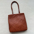 Brown handmade woven leather tote bag with a three-dimensional front pocket.