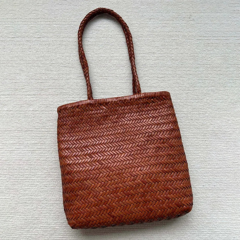 Brown handmade woven leather tote bag with a three-dimensional front pocket.