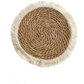 Round natural papyrus placemat on a wooden table, showing corn rope tassel detail and modern minimalist style.