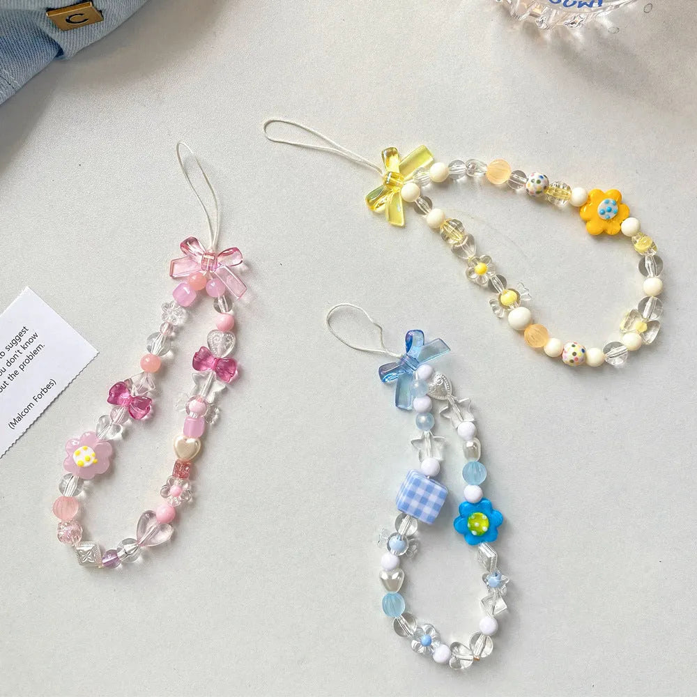Colourful beaded flower lanyard for mobile phones with blue, pink, or yellow plastic flowers on an adjustable rope strap.