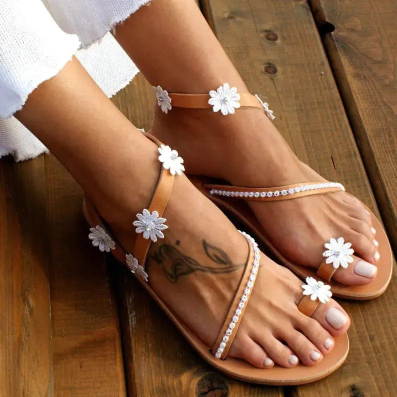 Brown women's Roman sandals with floral pattern, flat rubber sole, and herringbone toe design.