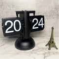 Small scale retro flip clock with black or white trim and black flip cards on a desk