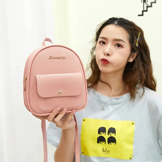 Black PU women's small backpack convertible to a shoulder bag, shown with a mobile phone for scale.
