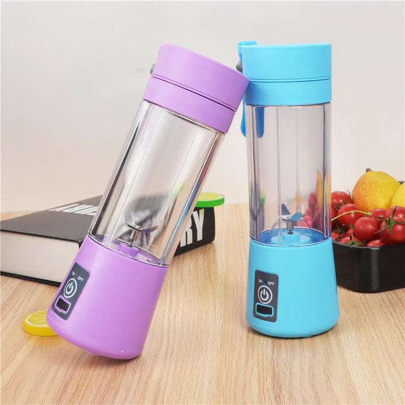 Mini USB electric fruit juicer with pink 400ml cup and stainless steel blades on a table.