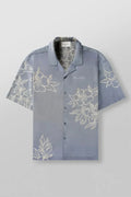 A loose-fitting short sleeve top with a floral print in a light colour, laid flat.