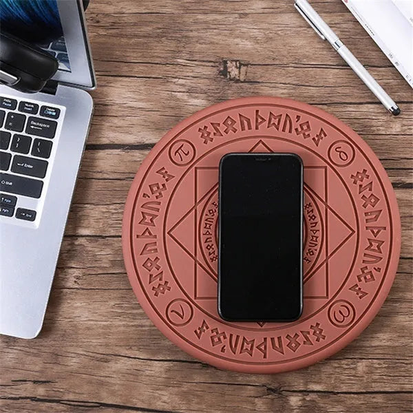 Square black wireless charging pad with glowing magic array pattern, charging a mobile phone.