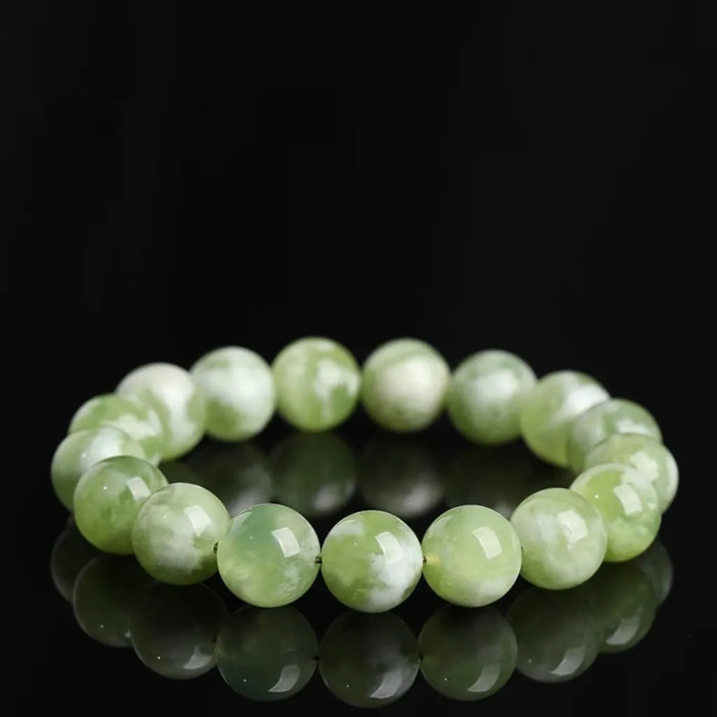 Polished green milk-in-water Xiuyan jade bracelet showing single circle of beads on a wrist.