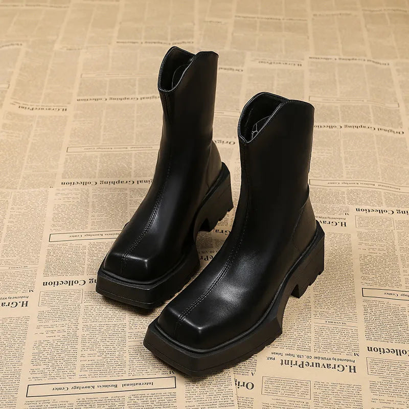 Women's black platform Martin ankle boots with a square toe and back zipper on a model.