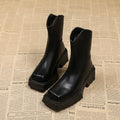 Women's black platform Martin ankle boots with a square toe and back zipper on a model.