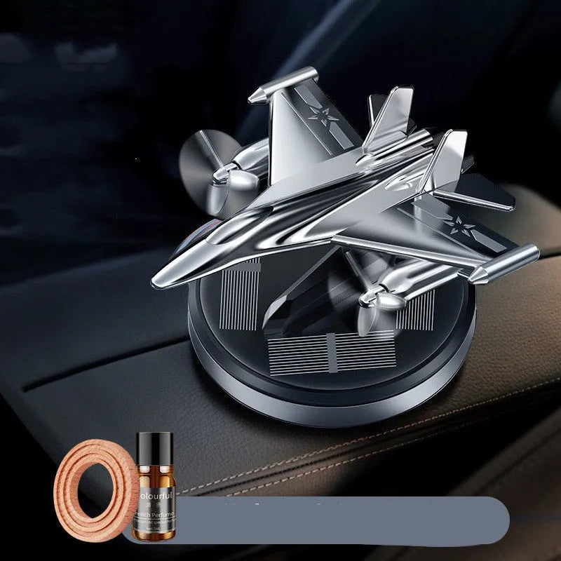 Silver solar powered rotating fighter jet perfume ornament on a wooden surface.