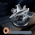 Silver solar powered rotating fighter jet perfume ornament on a wooden surface.