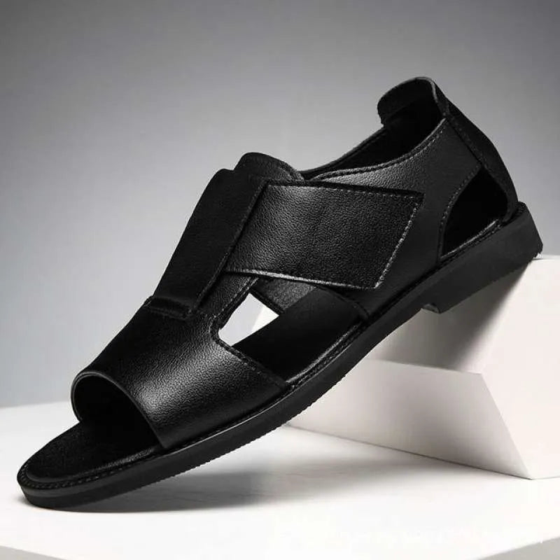 Men's black leather Roman sandals with open toe and non-slip rubber sole on a sandy beach.