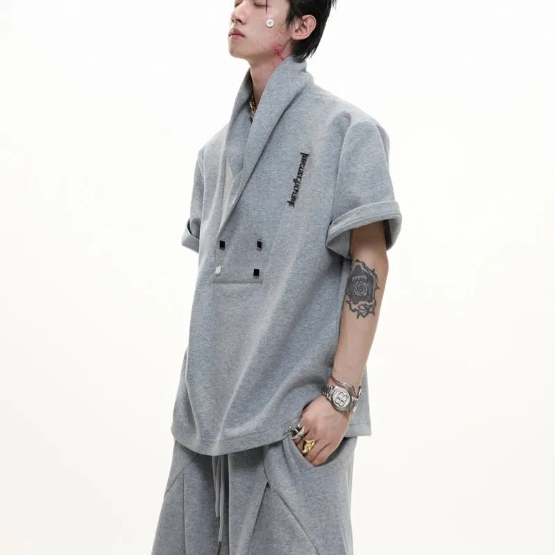 Men's dark grey cotton sports suit with V-neck jacket, padded shoulders, metal embellishments, and matching shorts.