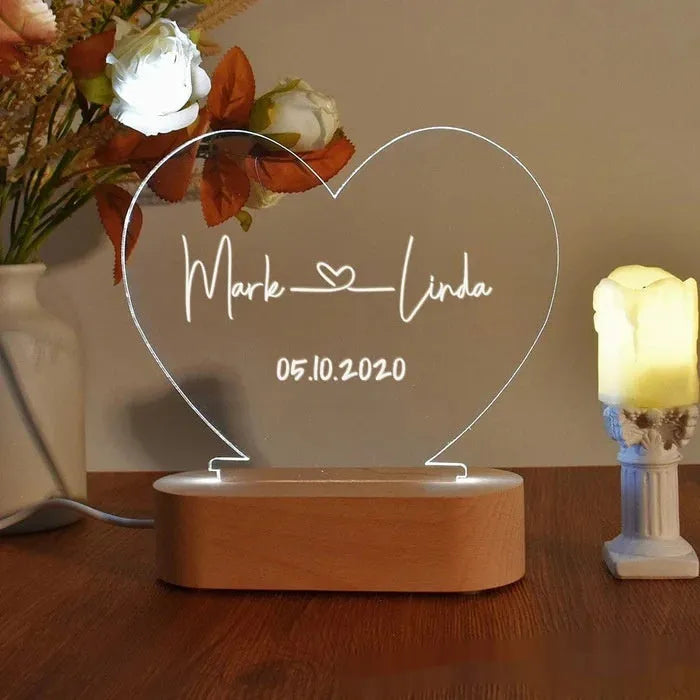 Custom transparent acrylic night light with personalised text, lit by LED, on a bedside table.