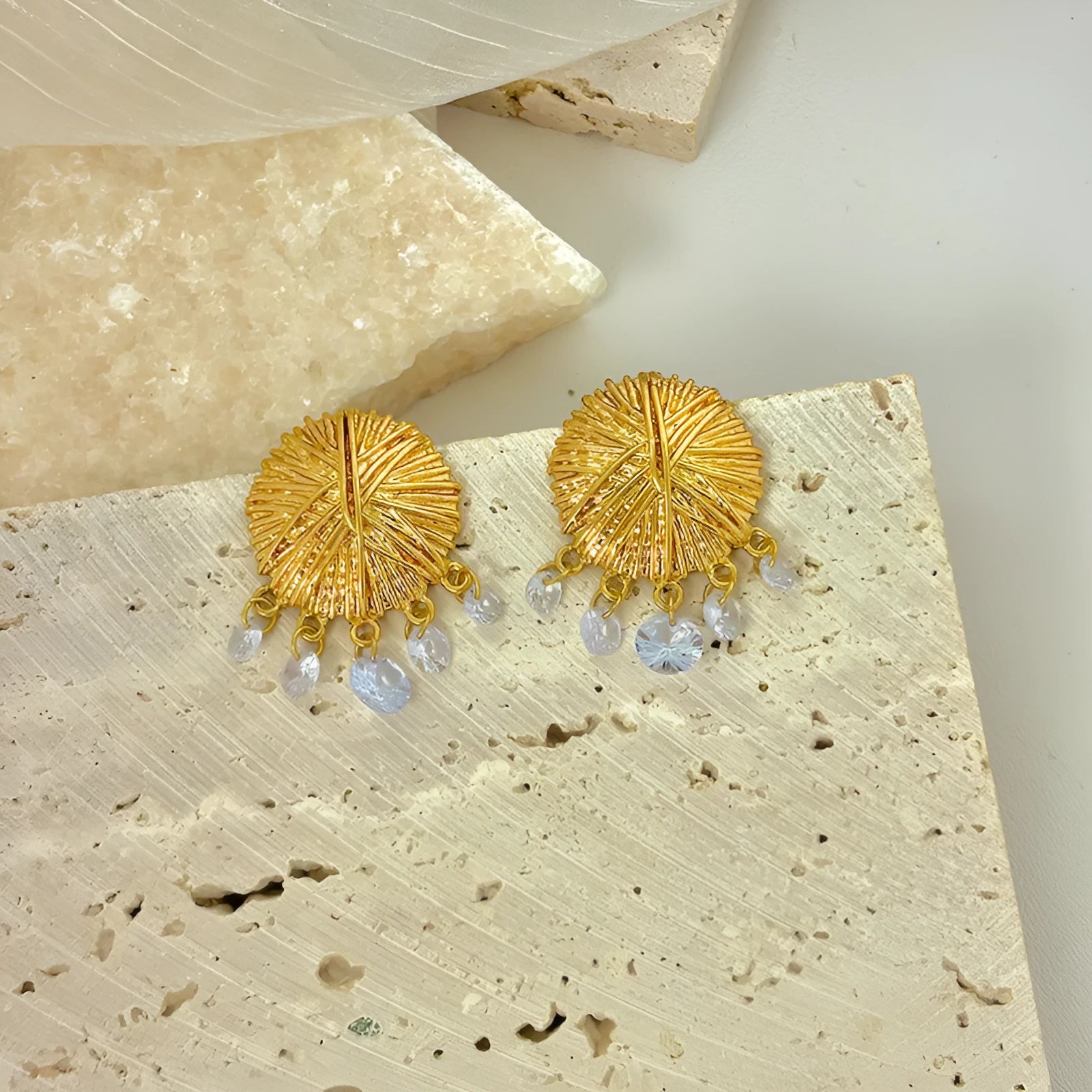 A pair of gold geometric metal earrings with round elements and an electroplated finish.
