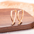 Rose gold coloured cross shaped earrings made from copper metal on a white background.