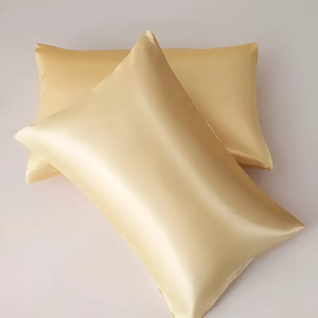 A pair of solid colour satin pillowcases in various colours and sizes on a bed.