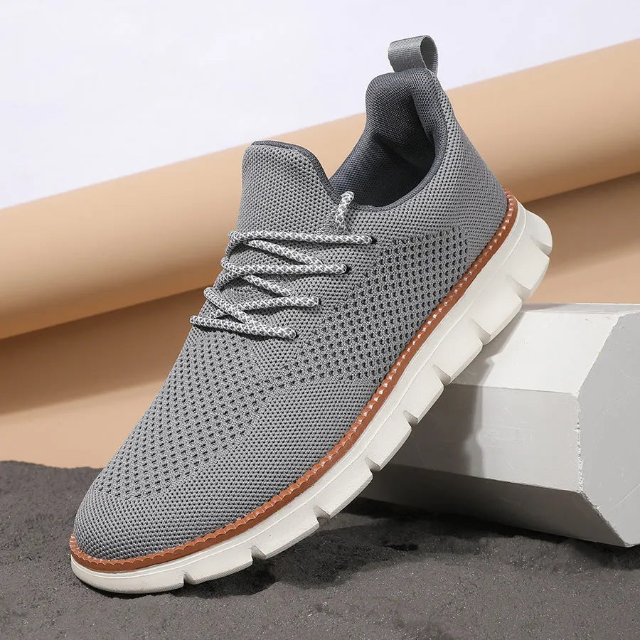 Men's grey and black low-top casual sneakers with woven mesh fabric upper and round toe.