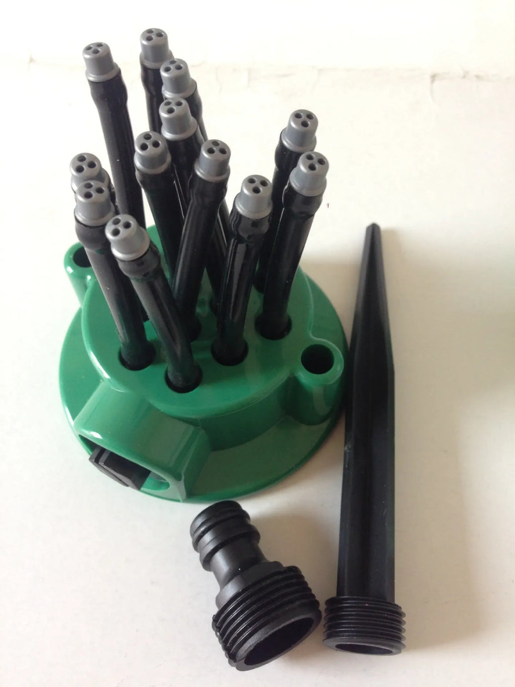 Green adjustable lawn sprinkler with flexible tubes for custom garden watering patterns