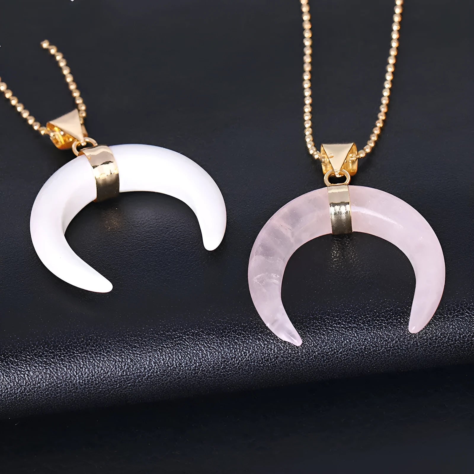 Close-up of a moon-shaped pink natural stone pendant on a metallic chain necklace.