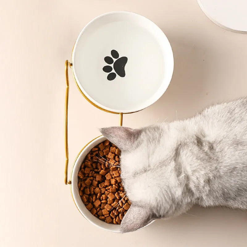White ceramic cat bowl with cat footprint design on a black iron stand with cat ears.