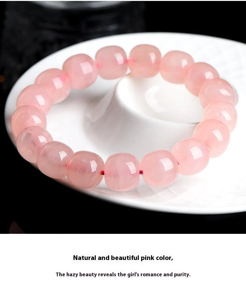 Close-up of a pink natural crystal barrel bead bracelet with geometric shaped beads on a wrist.