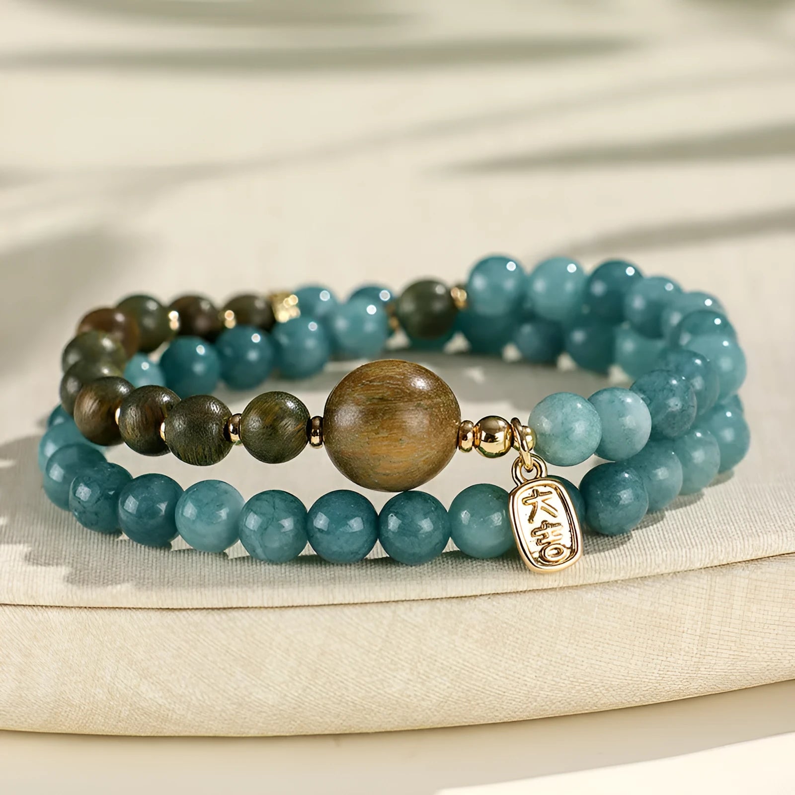 Close-up of a blue electroplated women's beaded bracelet with geometric and Fu/Xi character charms in New Chinese style.