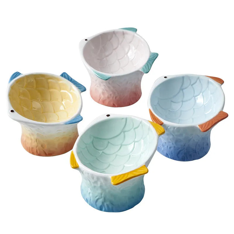 Set of blue fish-shaped ceramic cat bowls with a tilted angle on a wooden surface.