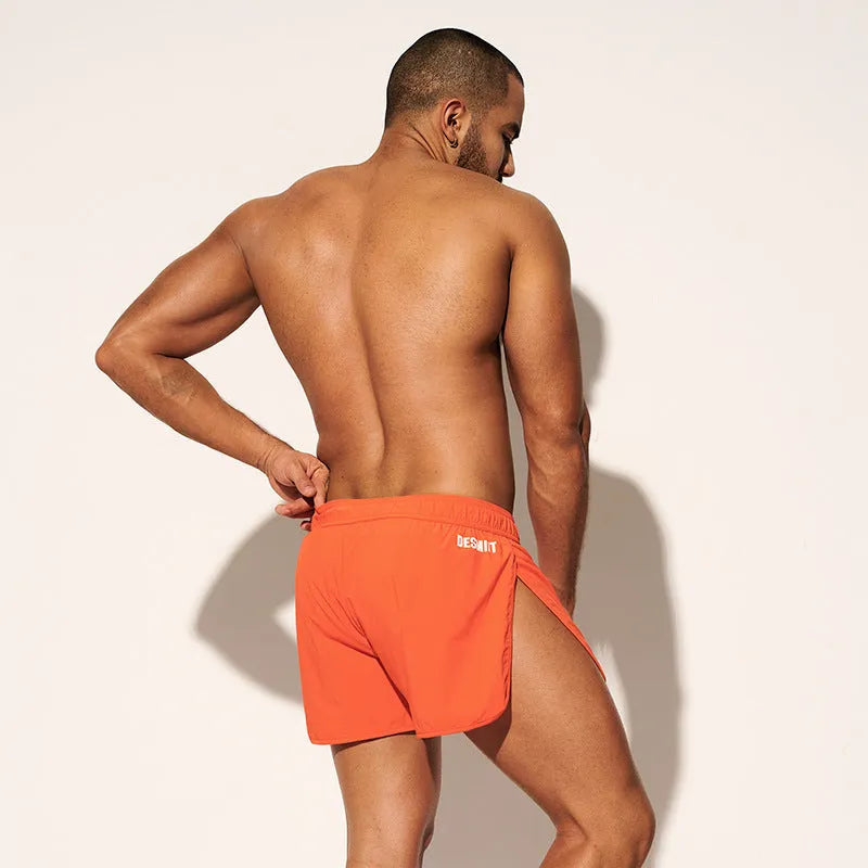 Man wearing loose orange red polyester beach shorts with micro elastic waist
