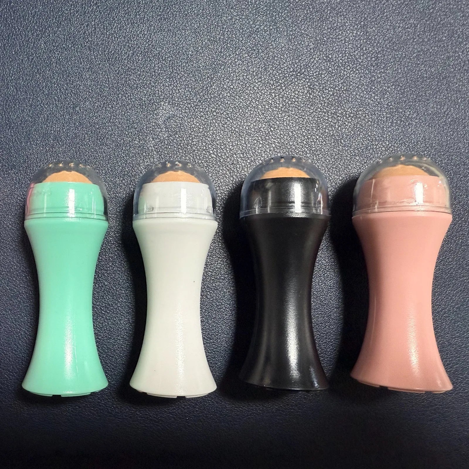 Volcanic stone portable roller for oily skin control in black, green, pink, or white.