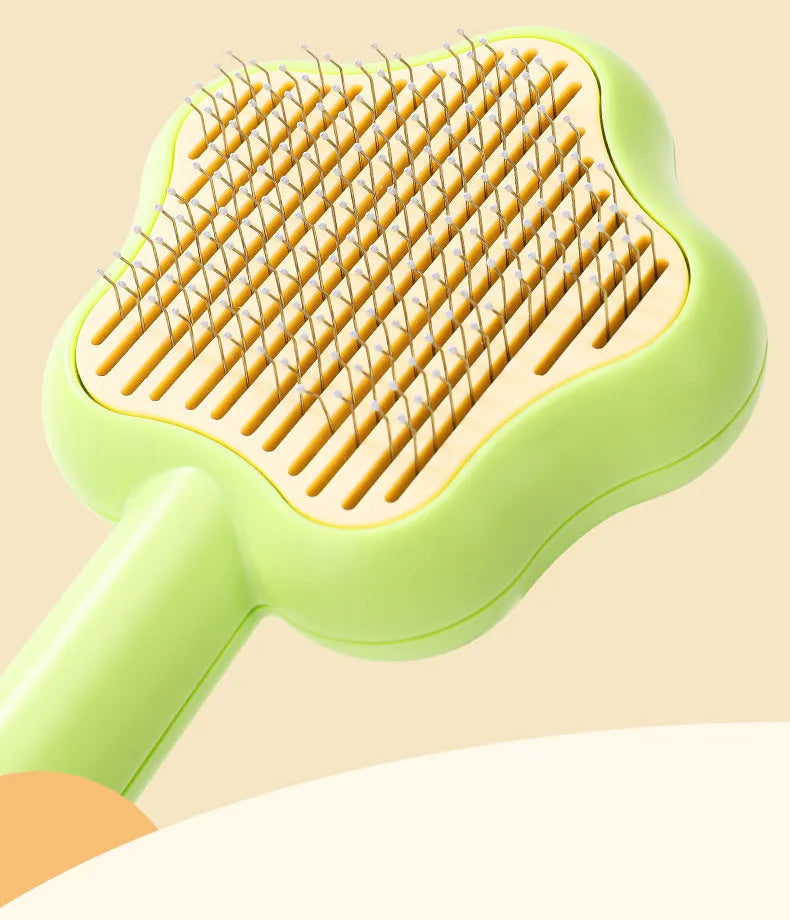 Green and yellow self-cleaning stainless steel cat comb with needle teeth on a wooden table.