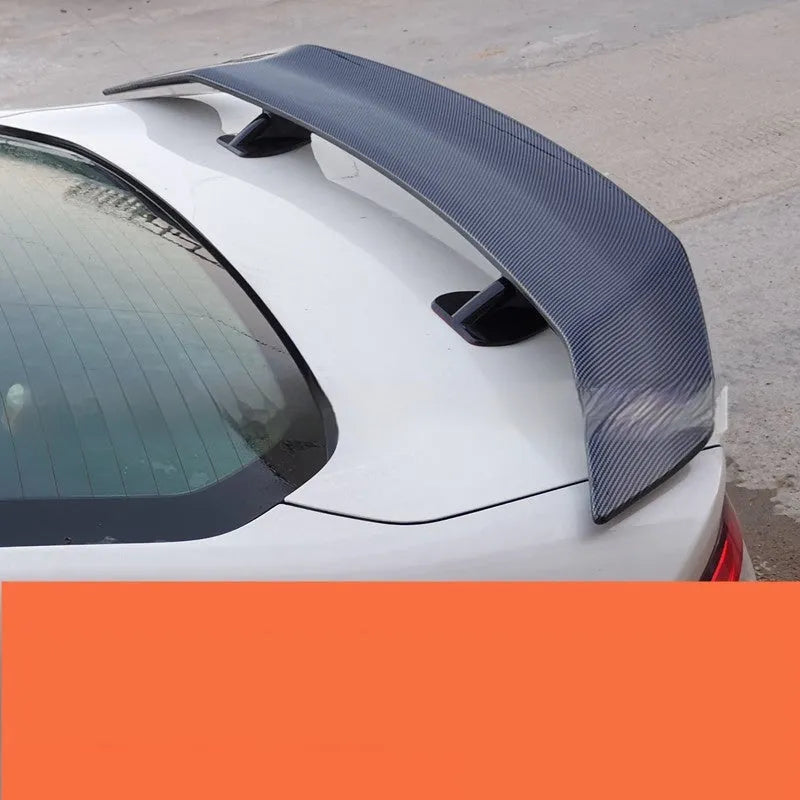 Universal punch-free car tail wing spoiler in ABS plastic shown in bright black and carbon pattern finishes.