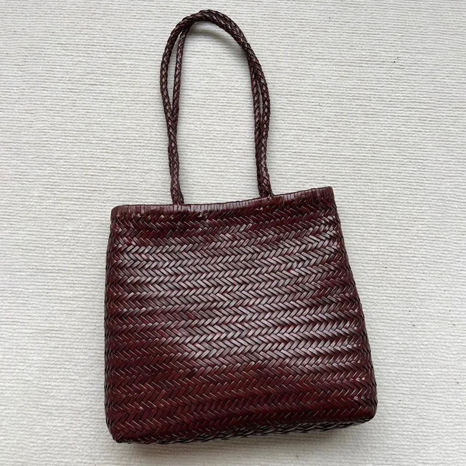 Brown handmade woven leather tote bag with a three-dimensional front pocket.