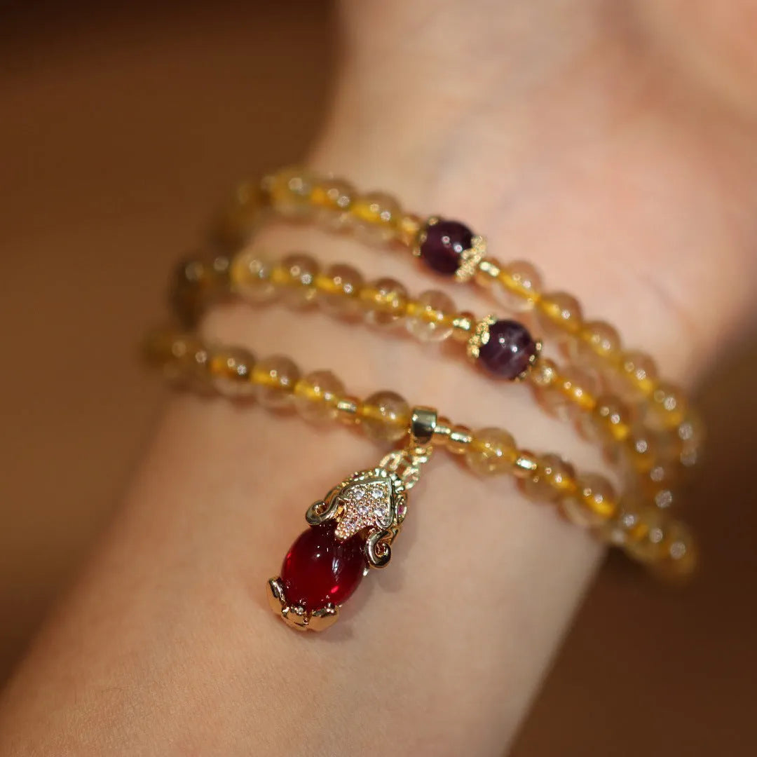 Handmade natural gold rutilated quartz bracelet with three gold circles and a chopsticks charm on a white background.
