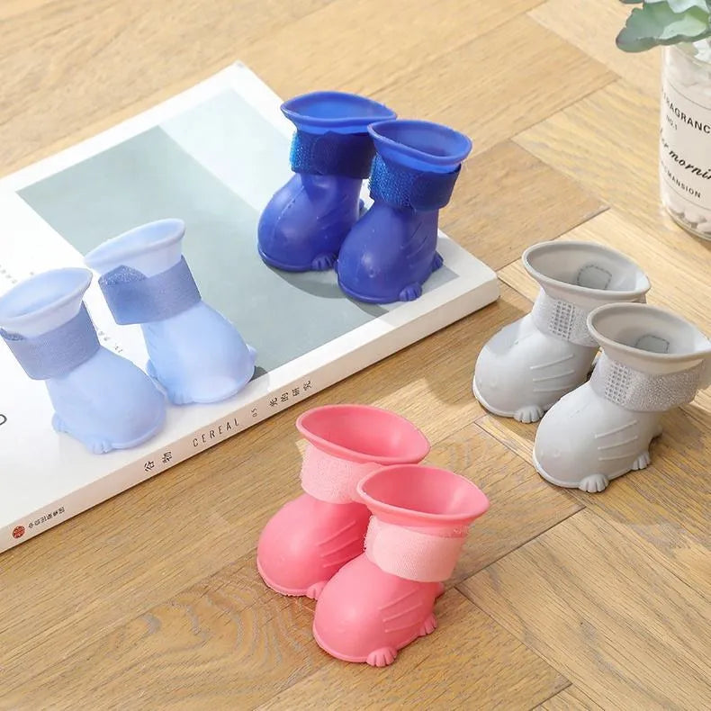 Four waterproof silicone dog rain boots in blue, grey, light blue and pink on a white background