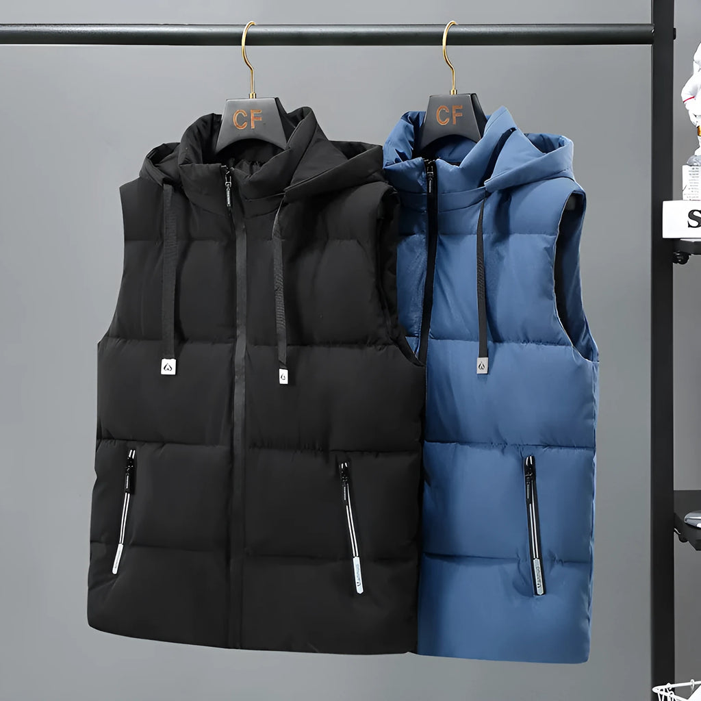 Man wearing a solid blue thickened vest with a removable hood and slant pockets.