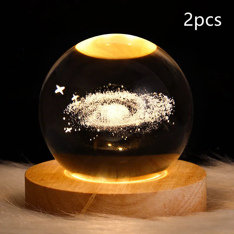 LED galaxy crystal ball night light with 3D planet designs on a table