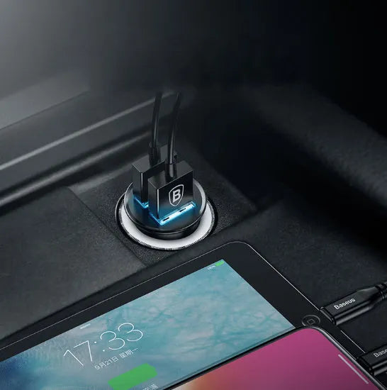 Black aluminium alloy dual USB smart car charger plugged into a 12V car socket.