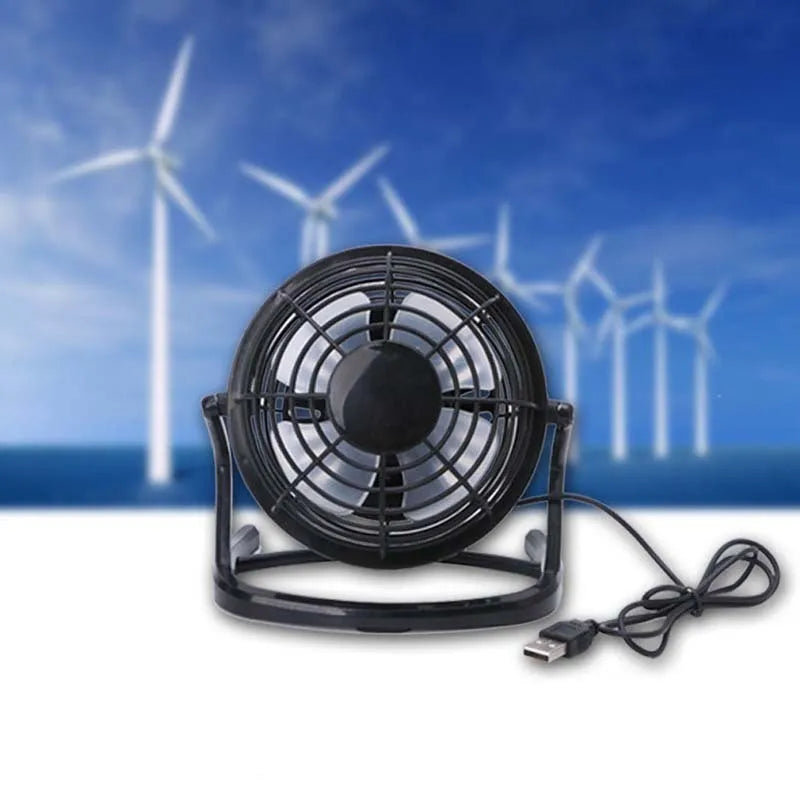 Black mini USB desk fan with adjustable angle on a wooden desk.