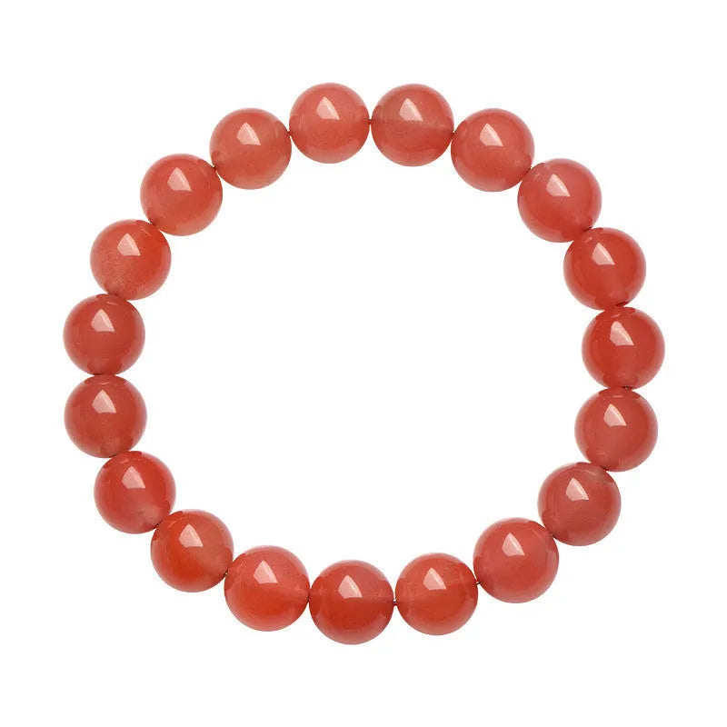 A close-up of a polished cherry red agate bead bracelet on a wrist.