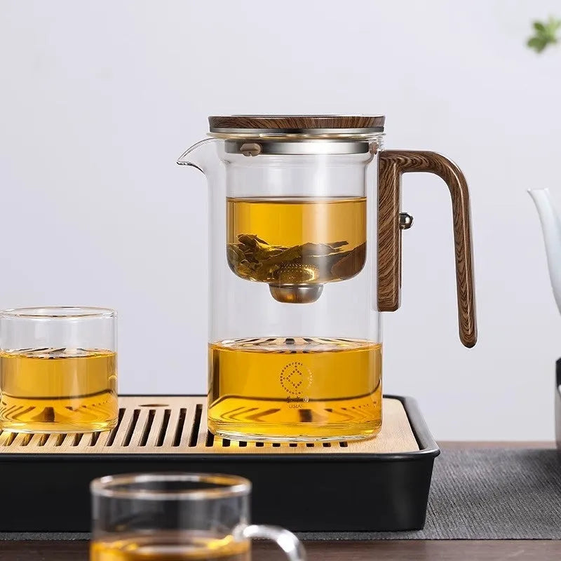 Chinese-style glass teapot with wooden handle showing magnetic filtration button and inner infuser container.