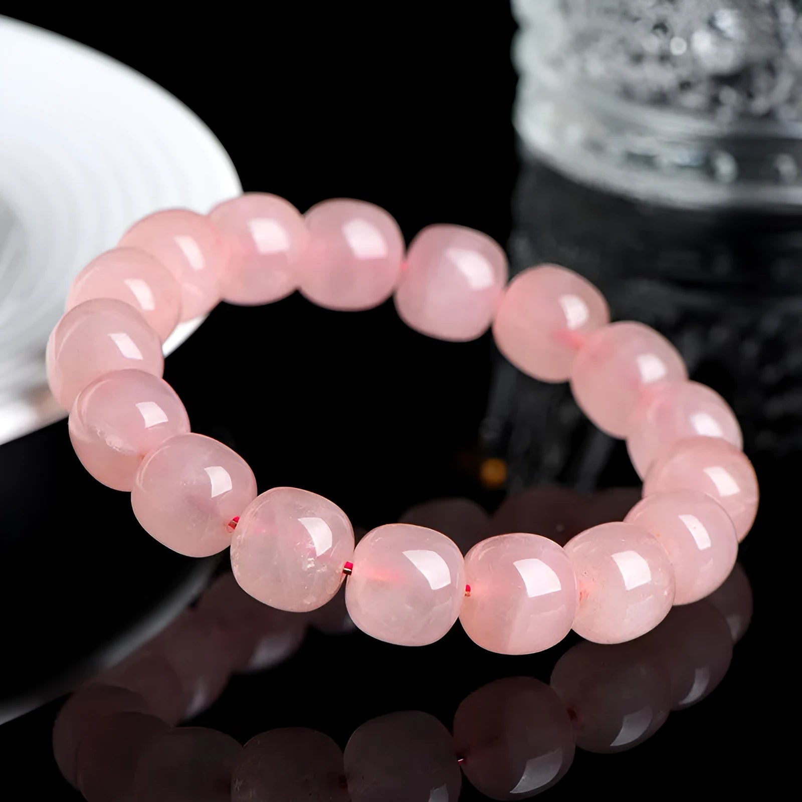 Close-up of a pink natural crystal barrel bead bracelet with geometric shaped beads on a wrist.