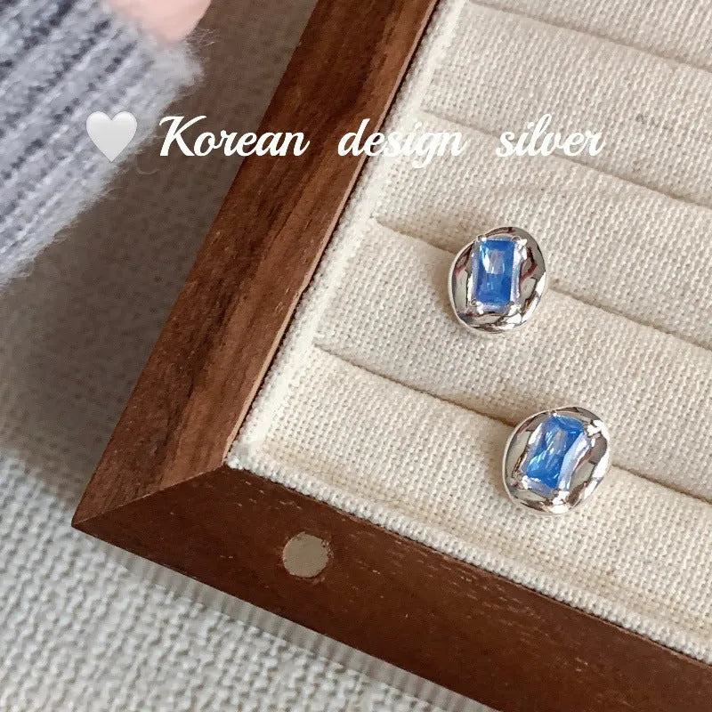 S925 sterling silver earrings with oval blue diamond heart-wrapped geometric design and electroplated silver finish